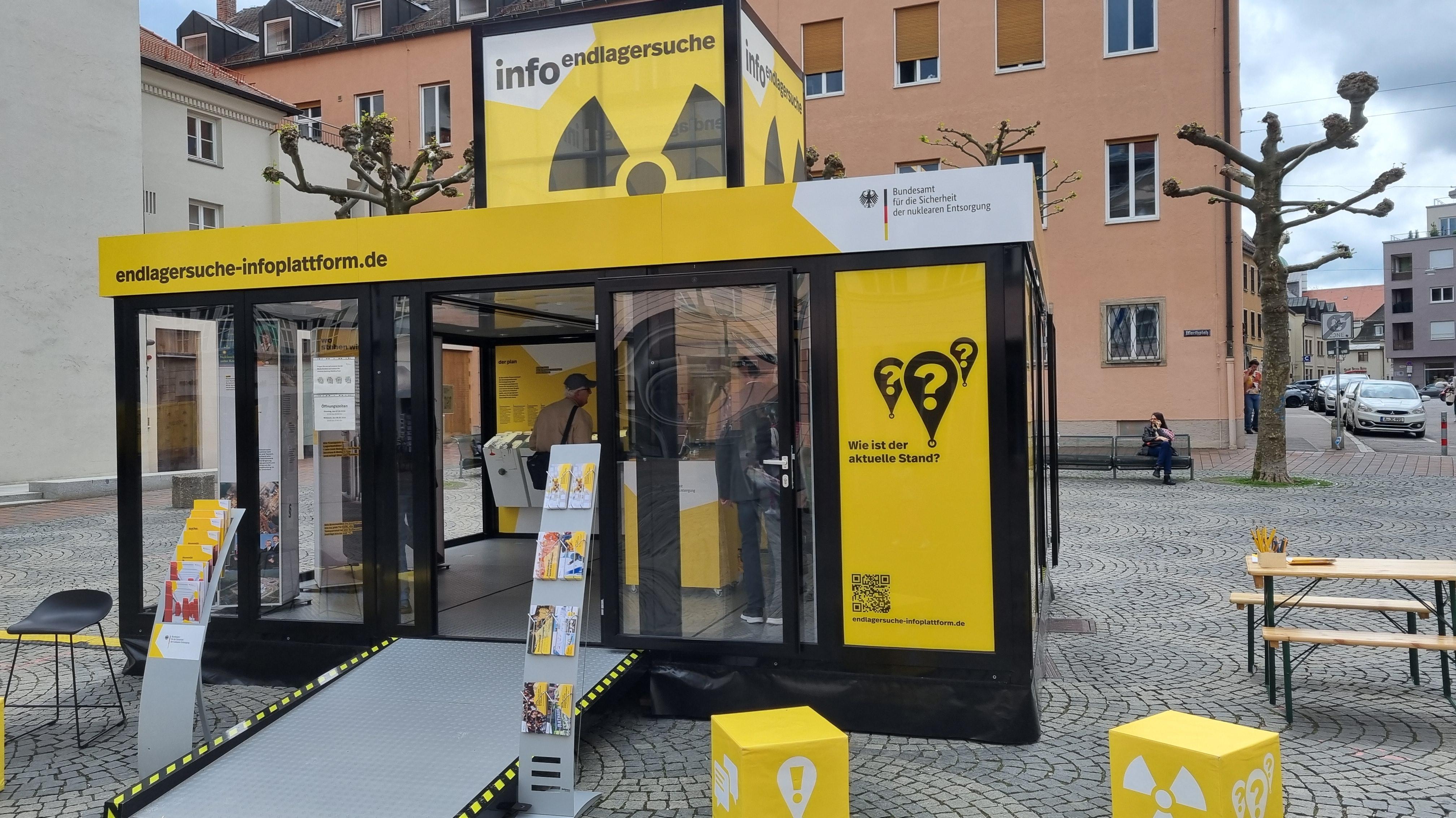 Ein gelber Infostand einer Bundesbehörde auf dem Augsburger Moritzplatz