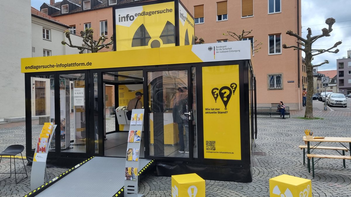 Ein gelber Infostand einer Bundesbehörde auf dem Augsburger Moritzplatz