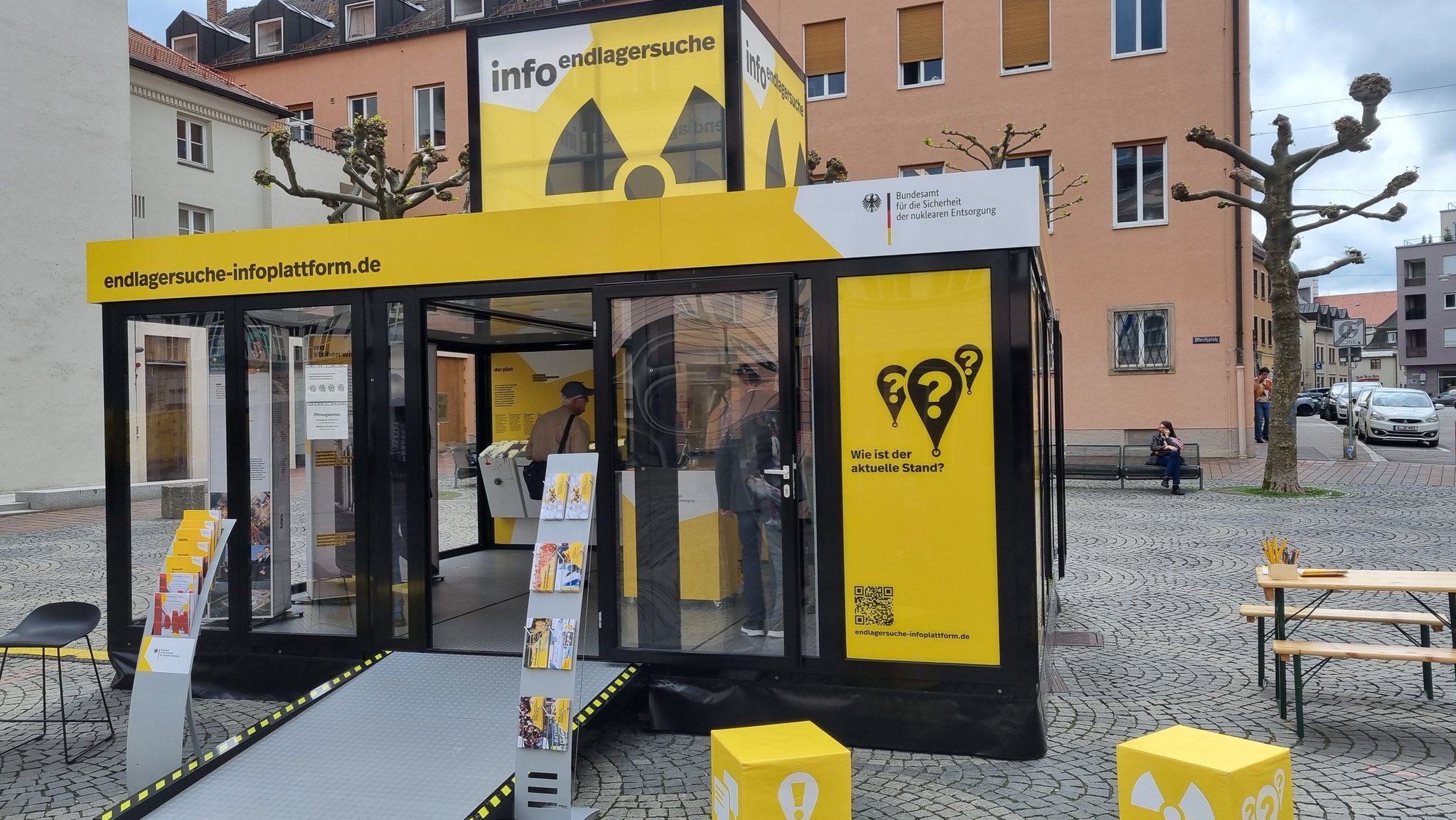 Ein gelber Infostand einer Bundesbehörde auf dem Augsburger Moritzplatz