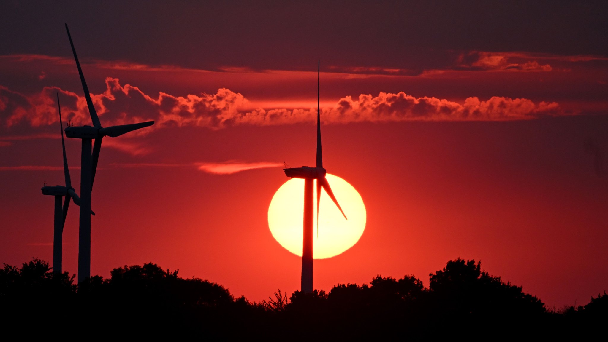 Hinter Windrädern färbt die sinkende Sonne den Himmel rot. Nach heißen Tagen sollen die Temperaturen am Sonntag in Nordrhein-Westfalen mit 24 bis 28 Grad wieder etwas kühler werden. | Bild: dpa-Bildfunk/Federico Gambarini Hinter Windrädern färbt die sinkende Sonne den Himmel rot. Nach heißen Tagen sollen die Temperaturen am Sonntag in Nordrhein-Westfalen mit 24 bis 28 Grad wieder etwas kühler werden.