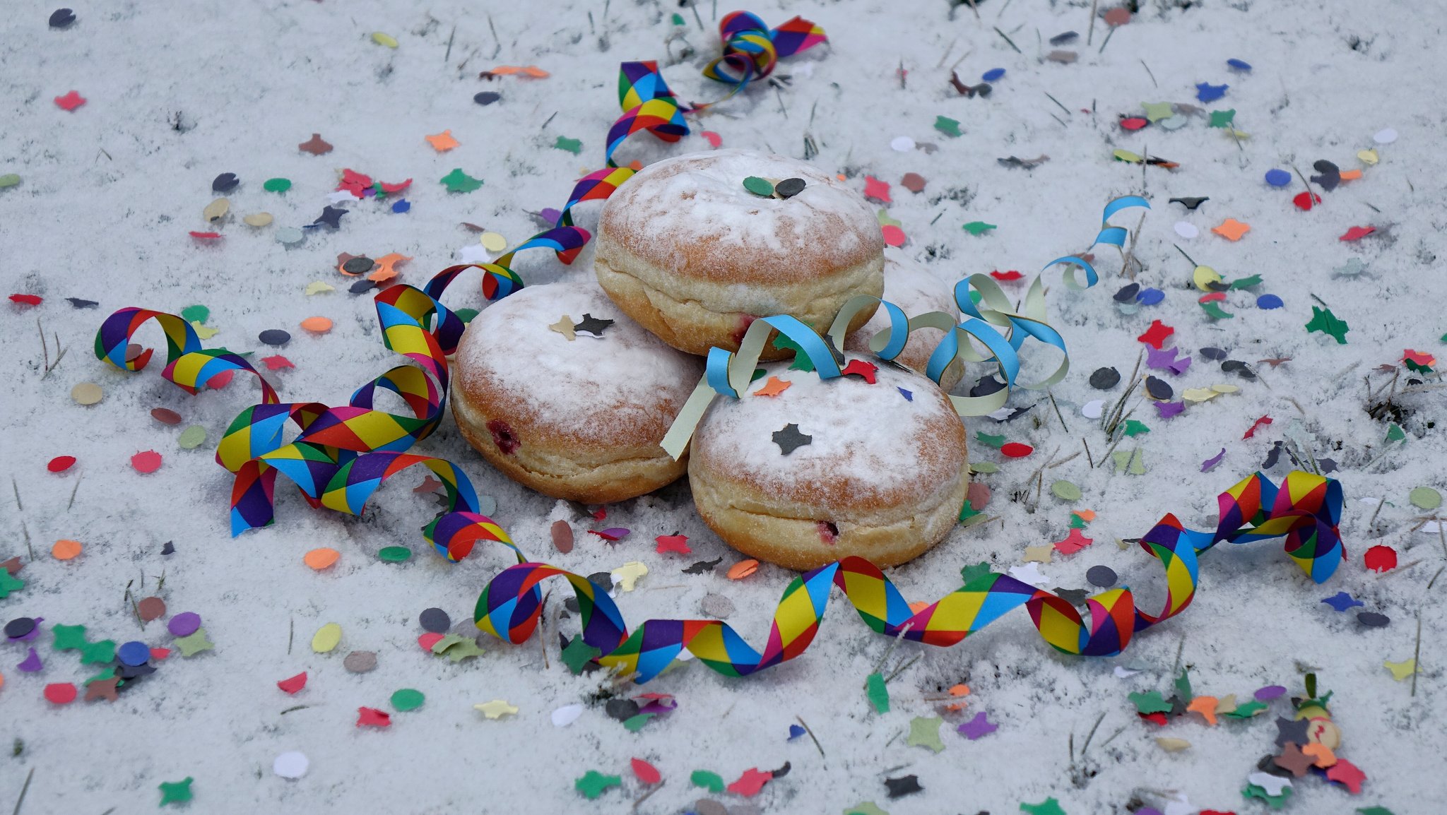 Symbolbild: Krapfen, Konfetti und Luftschlangen im Schnee