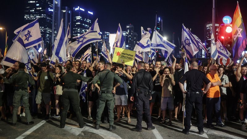 20.07.2023, Israel, Tel Aviv: Polizisten stehen vor Demonstranten während eines Protests gegen die israelische Regierung. 