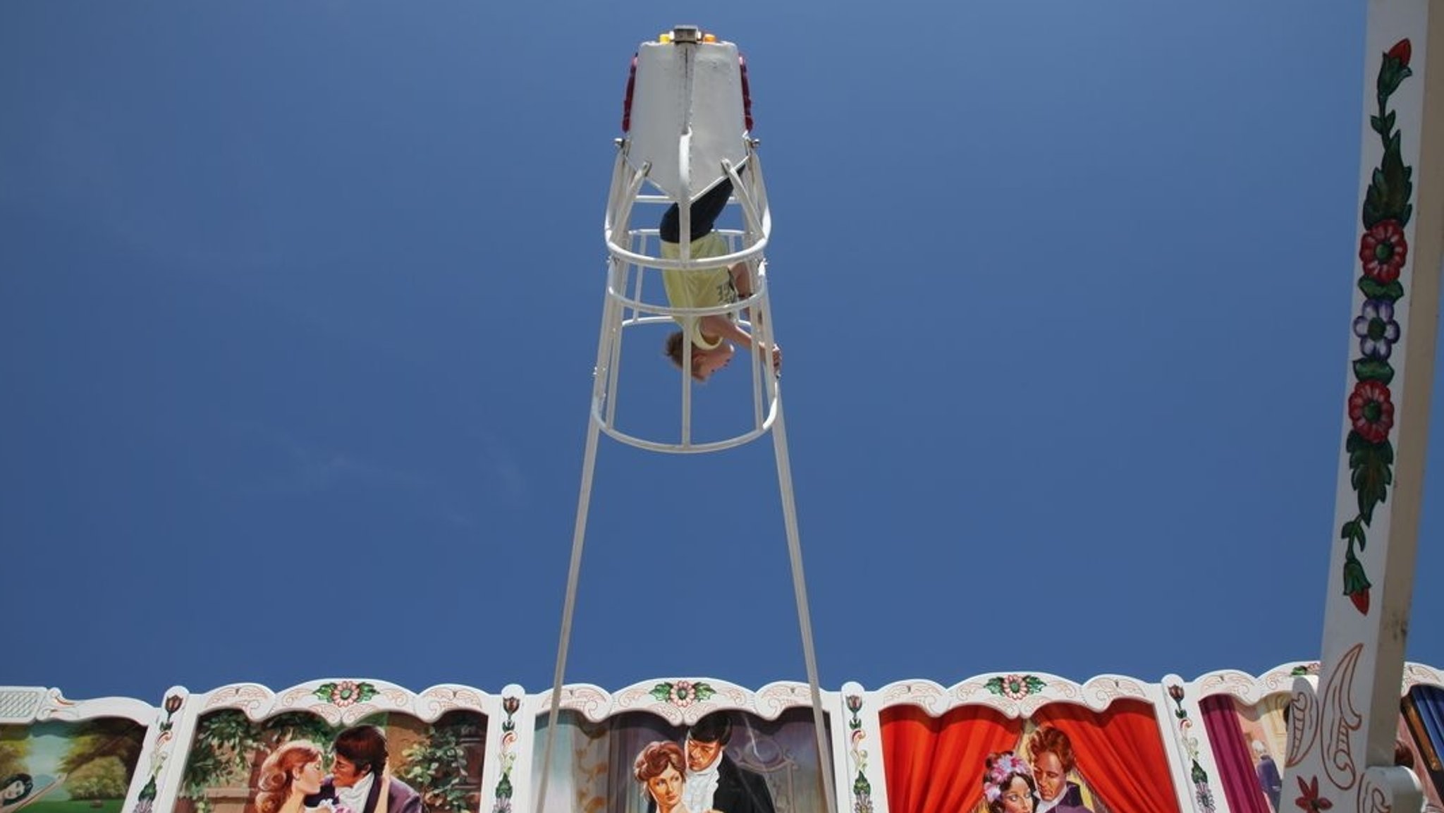 Oide Wiesn - Bub steht in Schiffschaukel und schwebt zum Himmel.