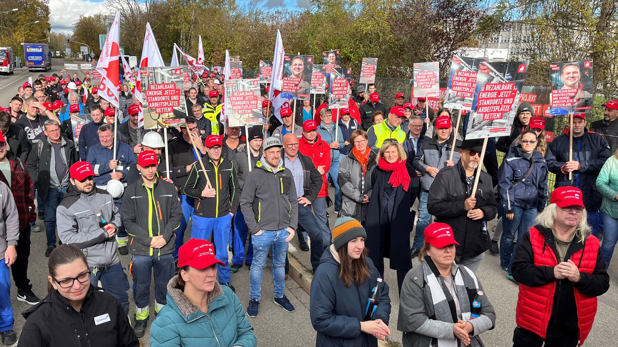 Kundgebung für einen Industriestrompreis in Gersthofen. Mit Plakaten und roten Mützen stehen die Demonstranten am Industriepark Gersthofen.