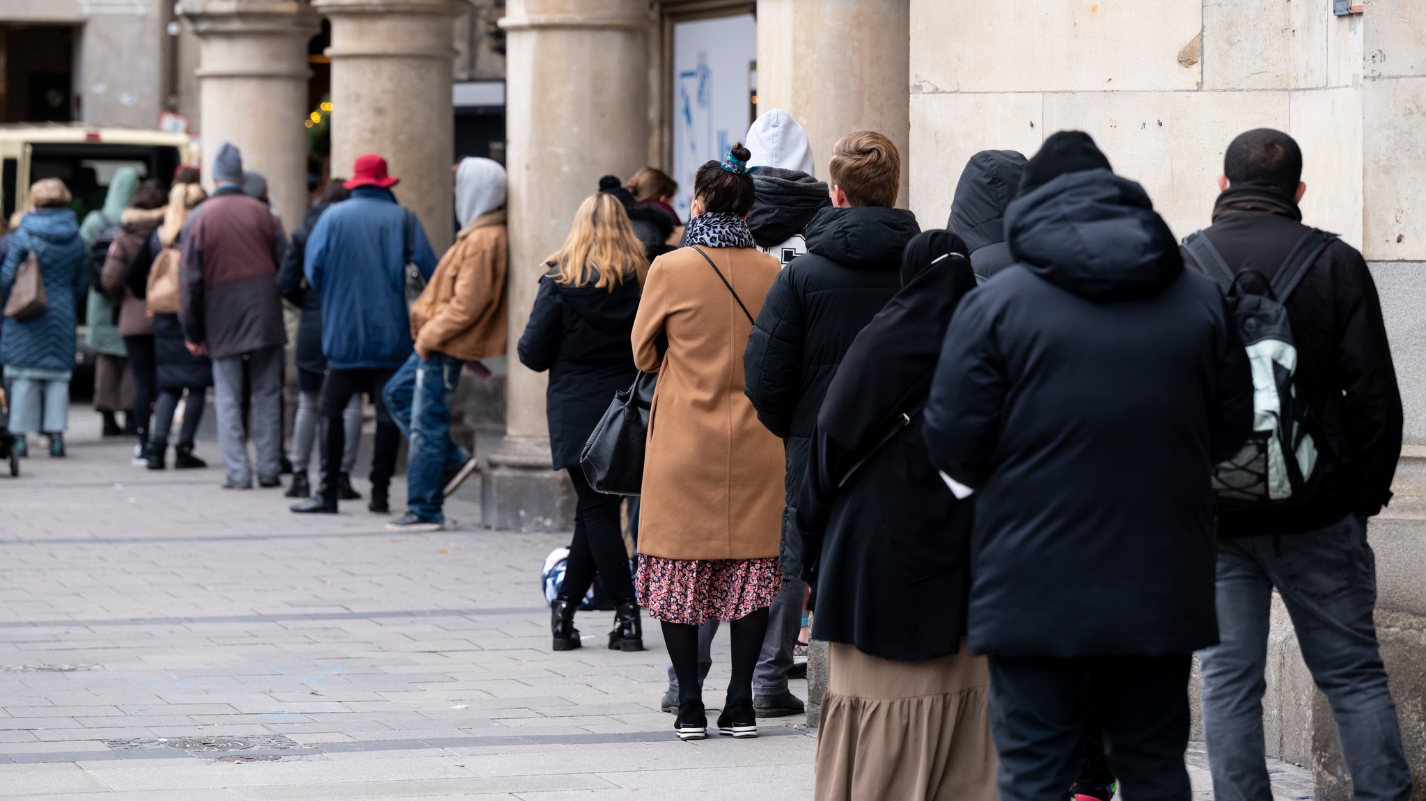 Zahlreiche Menschen stehen vor einem Impfzentrum in der Münchner Innenstadt in einer Warteschlange.