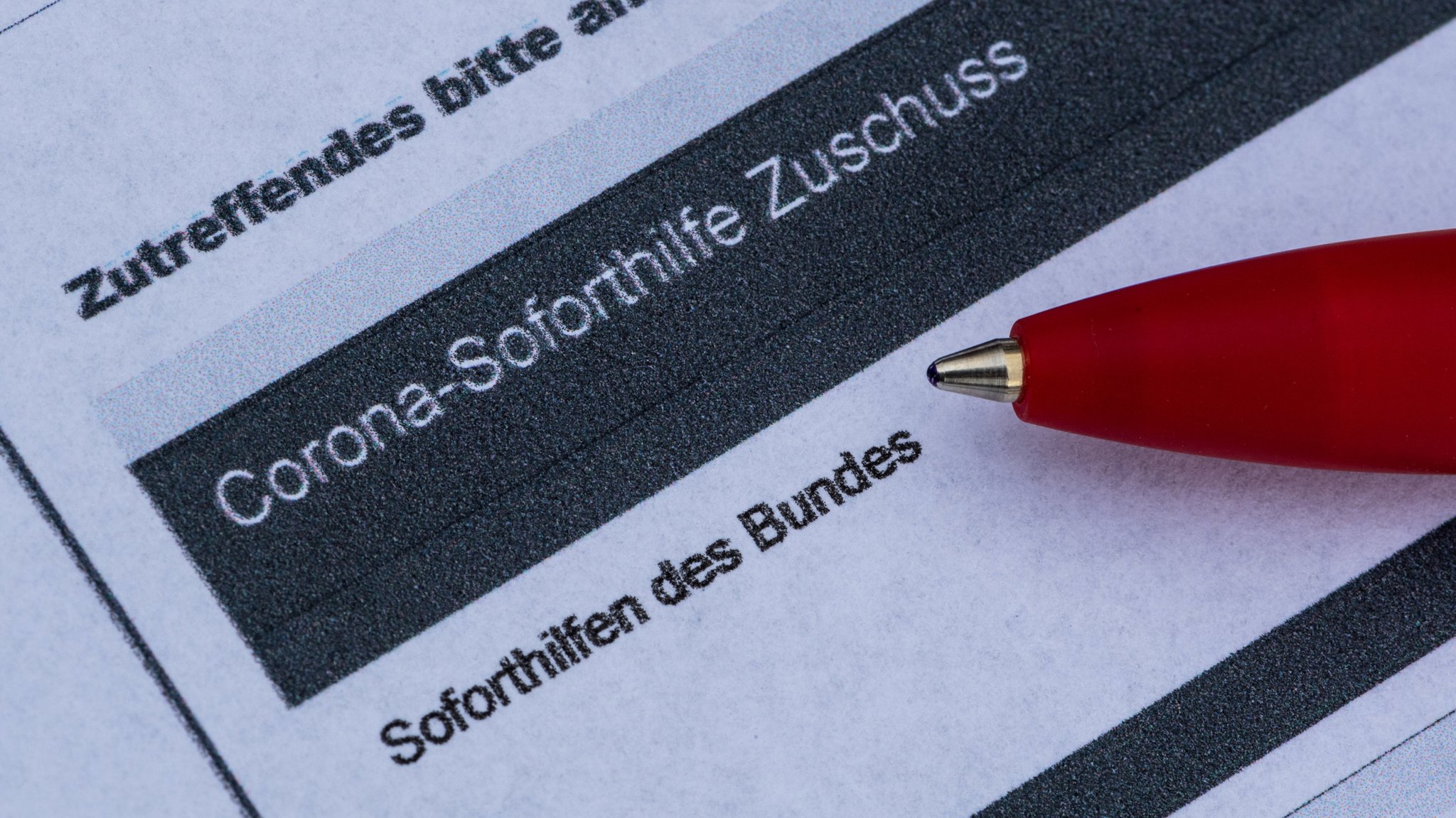 Ein Stift liegt auf einem Antrag für den Corona-Soforthilfe-Zuschuss des Bundes.