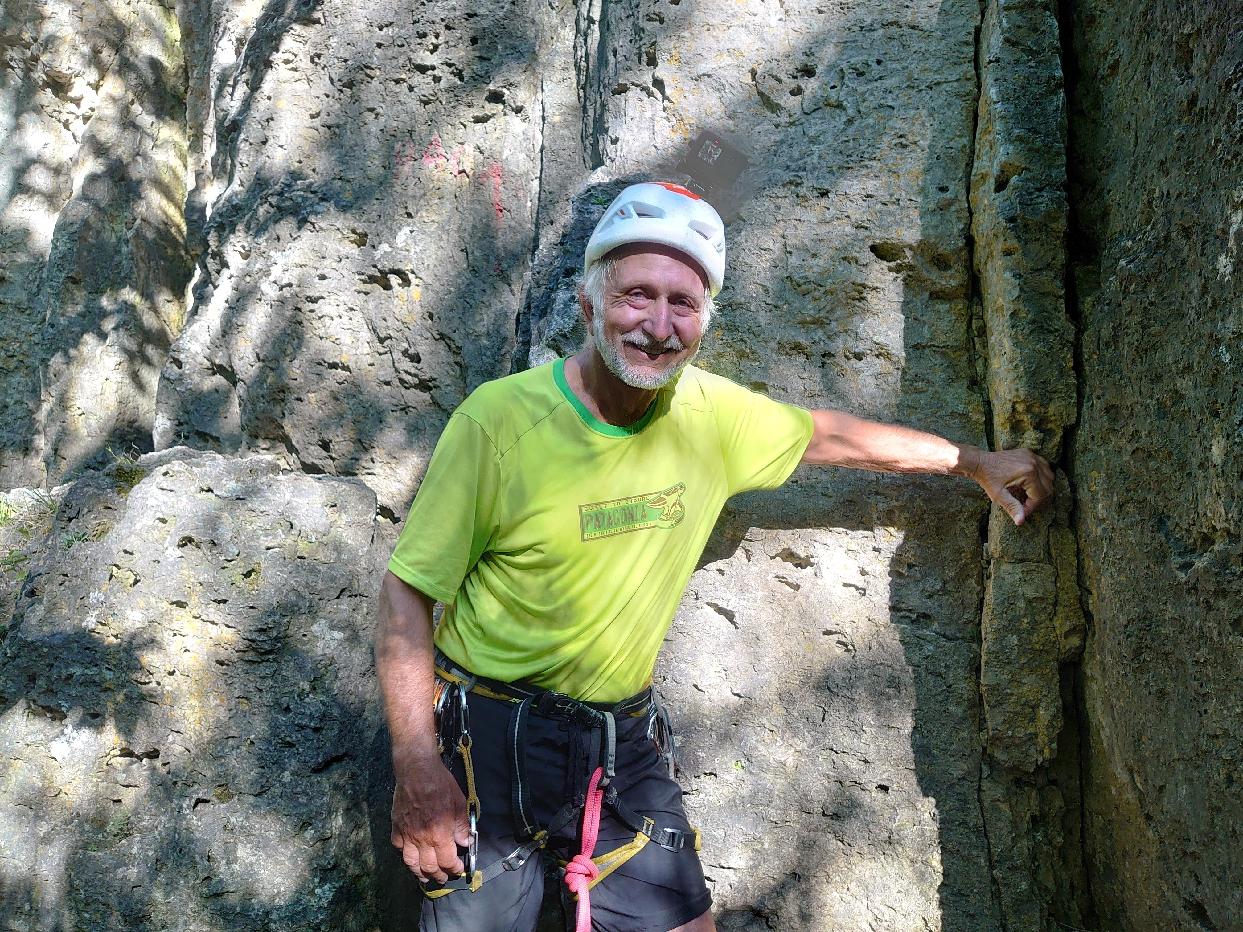 Immo Engelhard steht mit Klettergurt und Helm vor dem Röthelfels.