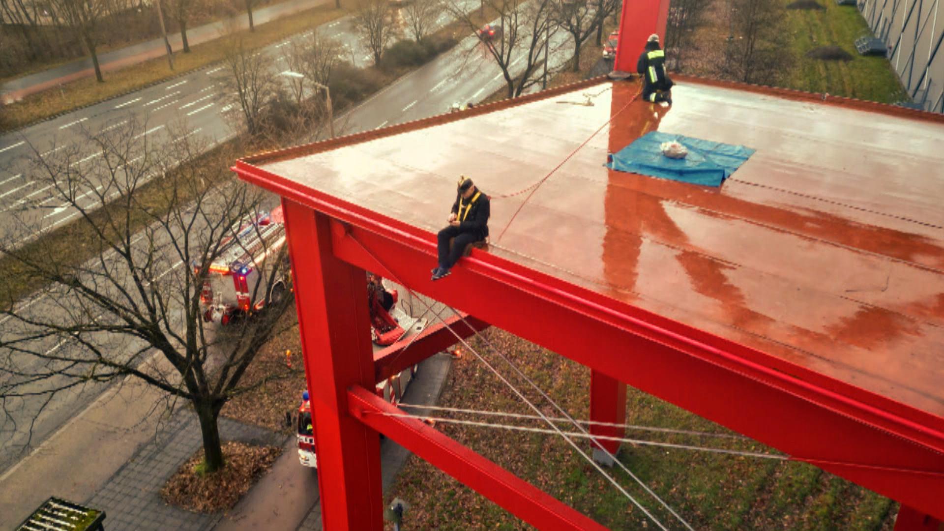 Ein Feuerwehrmann sitzt auf dem bekannten, riesigen, roten Stuhl eine Nürnberger Möbelhauses.