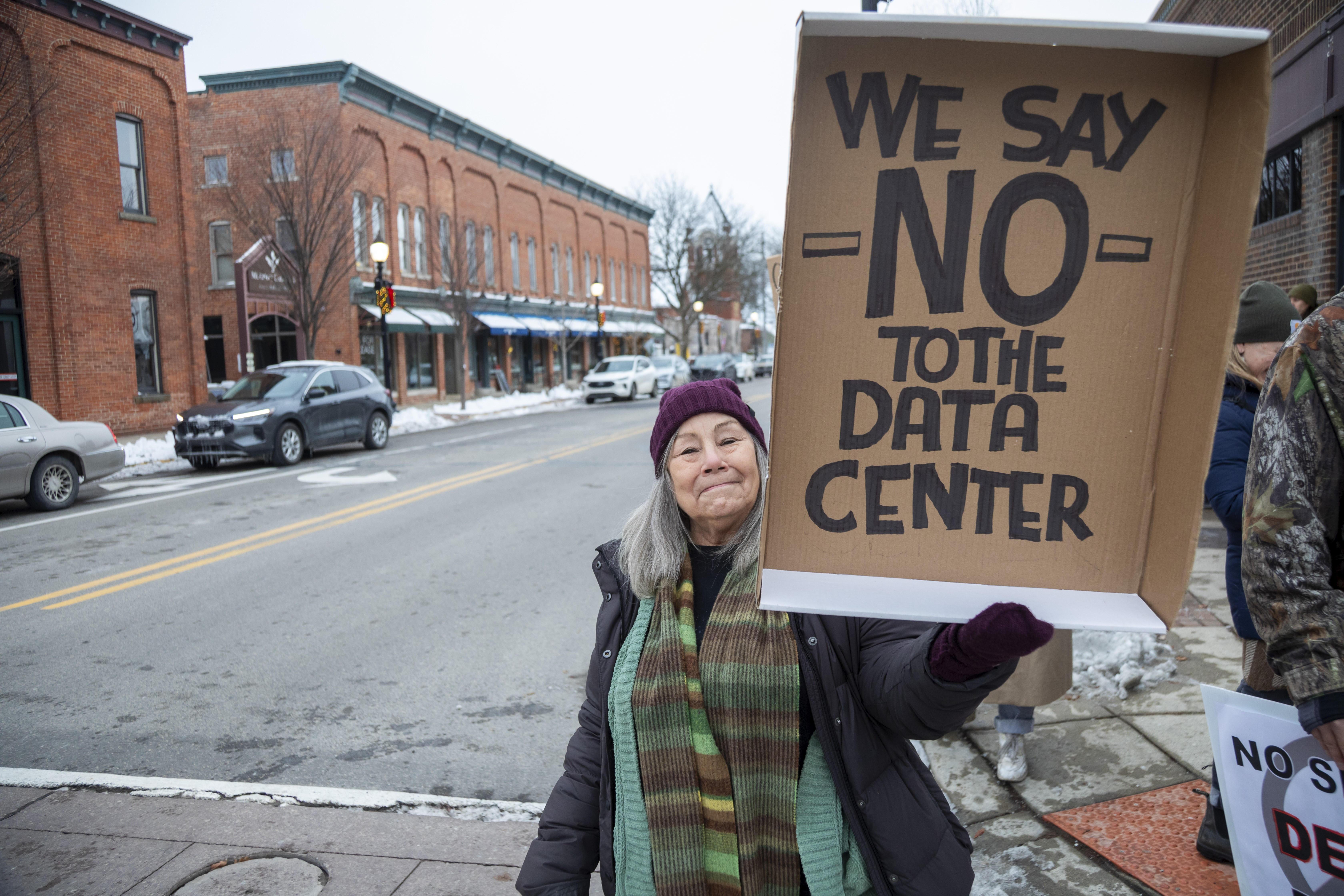 (Symbolbild) Frau hebt Schild mit Anti-KI-Parole; darauf steht: "We say NO to the Data Center"