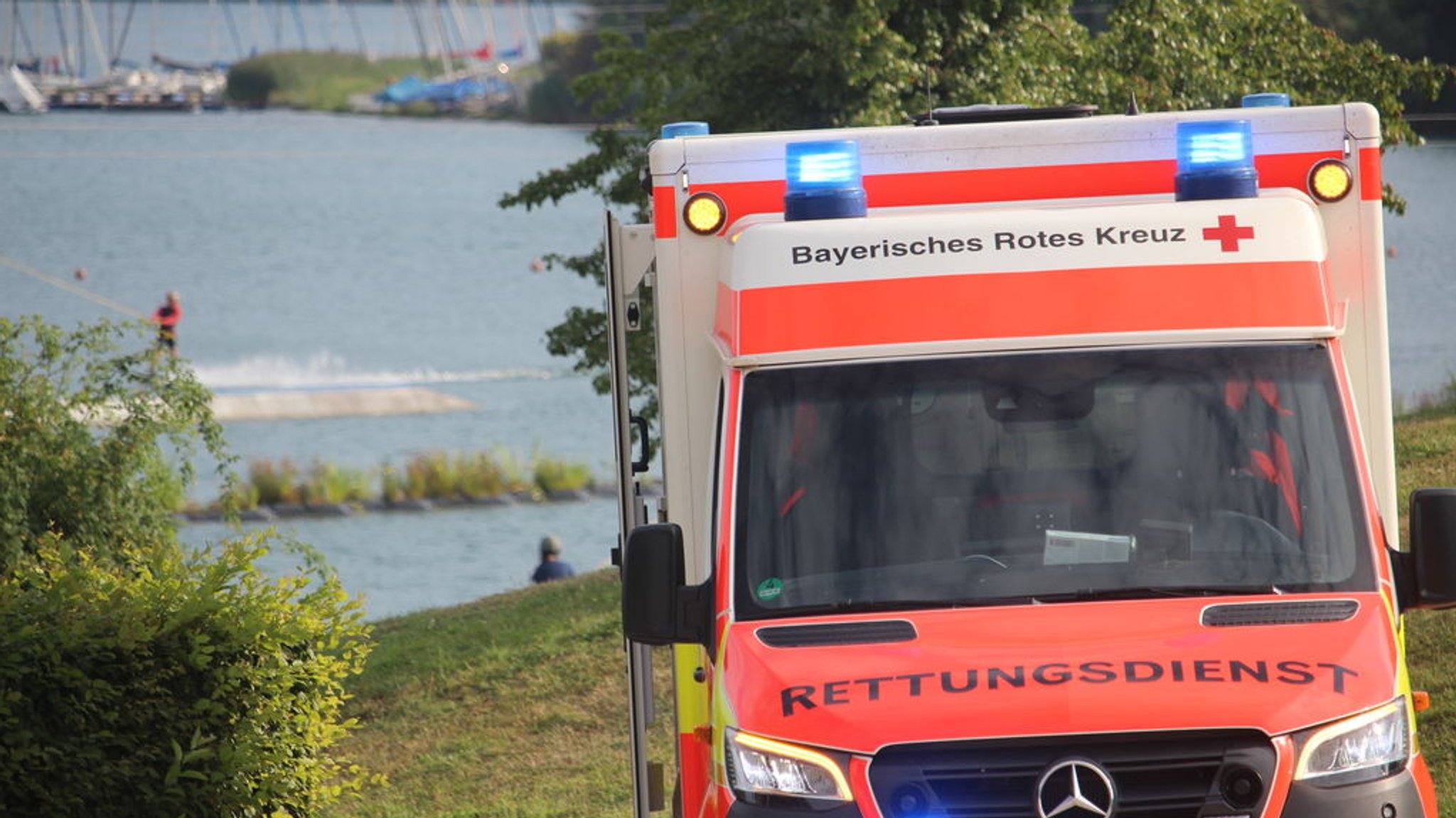 (Symbolbild) Ein Krankenwagen steht an einem Badesee.