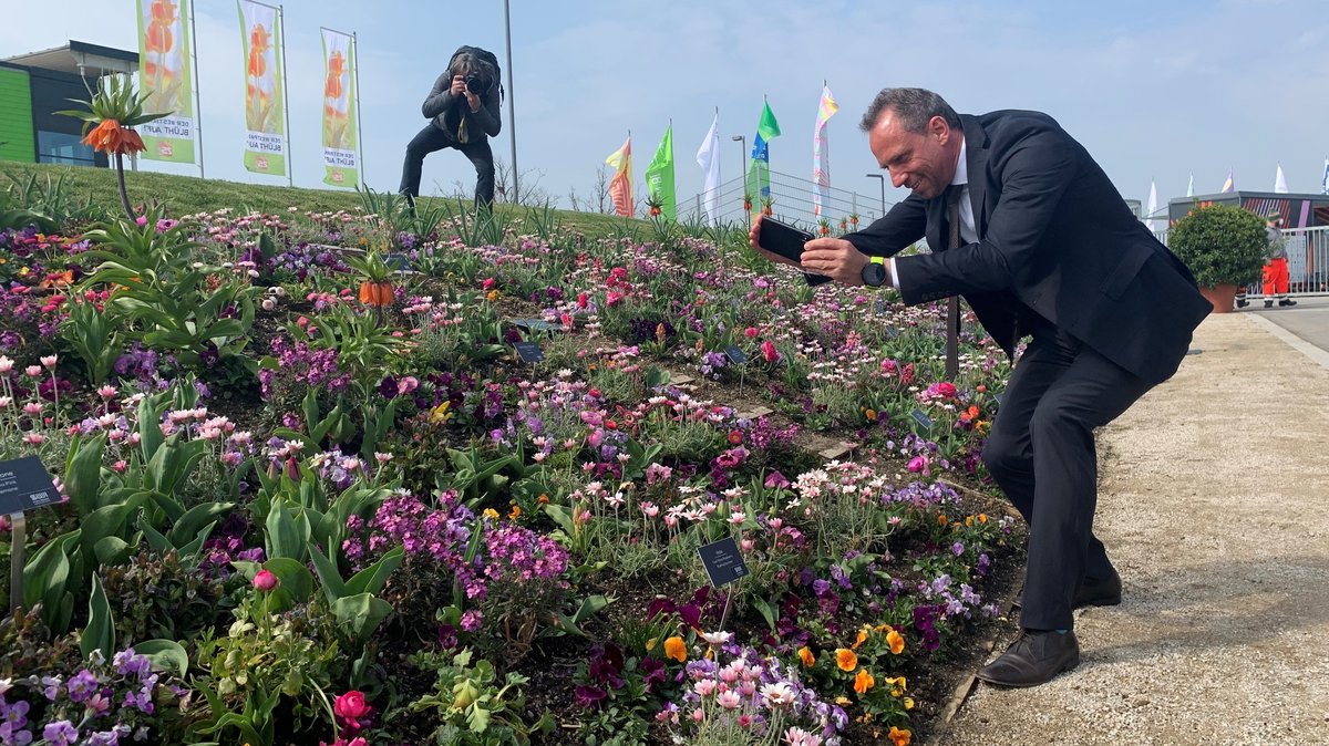 Umweltminister Thorsten Glauber fotografiert Blumen auf der neu eröffneten Landesgartenschau.