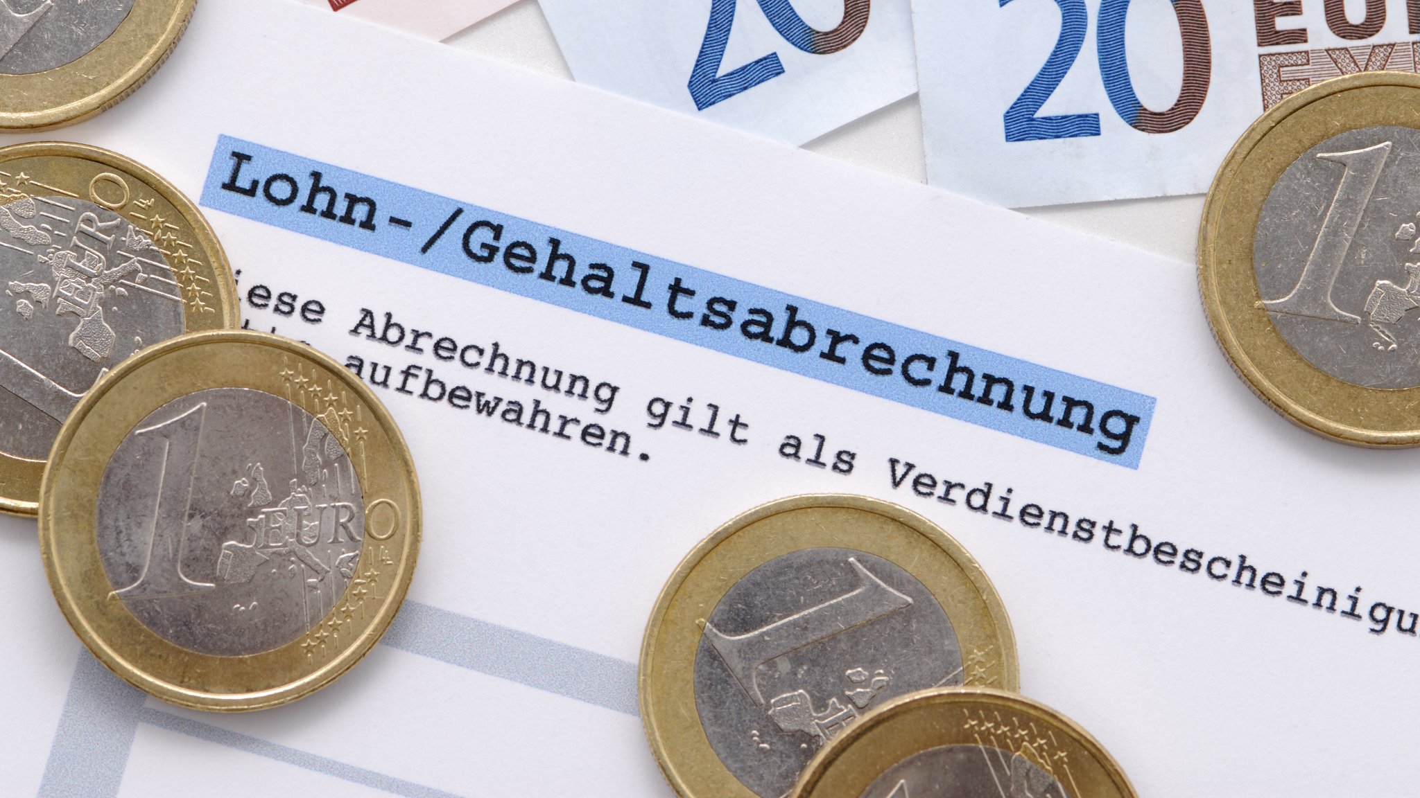 Gehaltsabrechnung mit Euro-Münzen und -scheinen