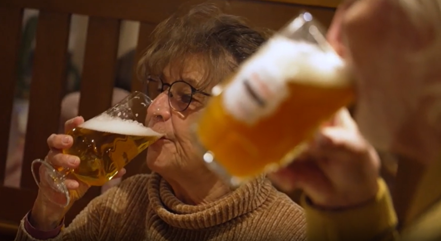 Zwei Menschen trinken in einer Gastwirtschaft aus Biergläsern alkoholfreies Bier.