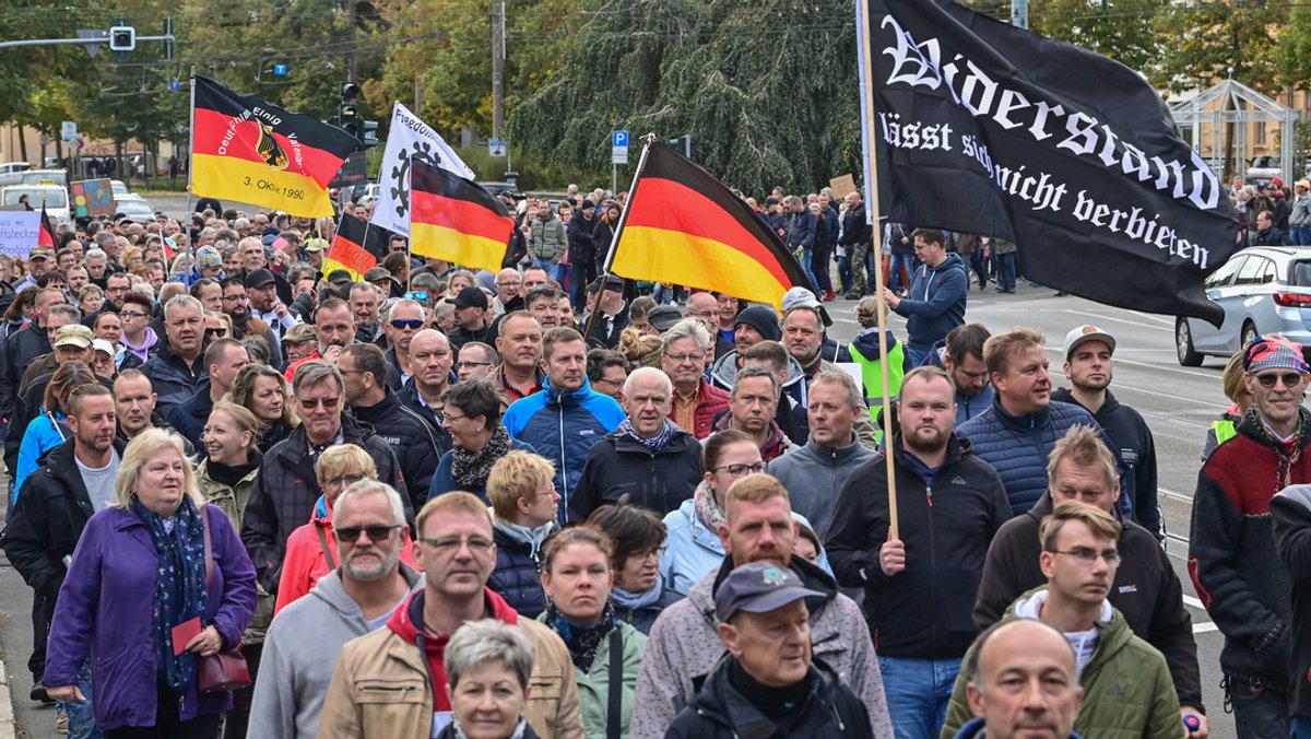 Menschen nehmen an einer Demonstration im Stadtzentrum teil. Ein Mann trägt dabei eine schwarze Fahne mit der Aufschrift "Widerstand lässt sich nicht verbieten". Anlass waren die Energiekrise, der Ukraine-Krieg und die Corona-Politik. 
