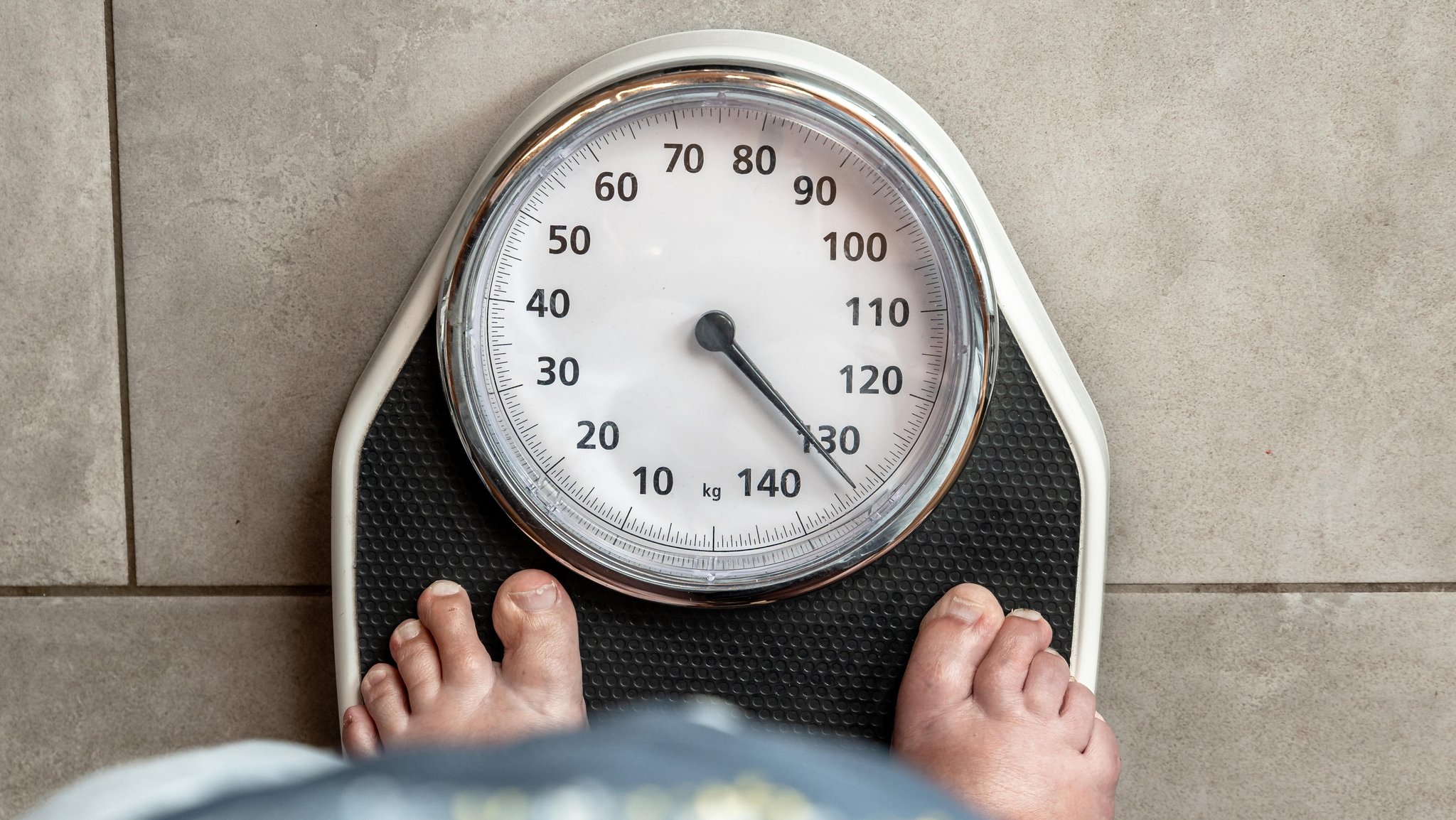 Eine erwachsene Frau steht barfuß auf einer Personenwaage, der Zeiger liegt über 130 kg. Symbolbild Körpergewicht, Gesundheit und Übergewicht | Bild: picture alliance / CHROMORANGE | Michael Bihlmayer Eine erwachsene Frau steht barfuß auf einer Personenwaage, der Zeiger liegt über 130 kg. Symbolbild Körpergewicht, Gesundheit und Übergewicht