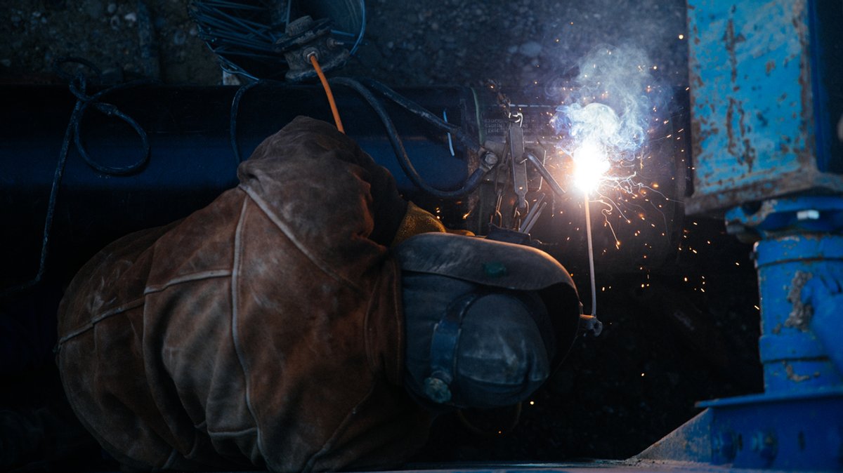Ein Bauarbeiter schweißt Rohre auf einer Baustelle zusammen.