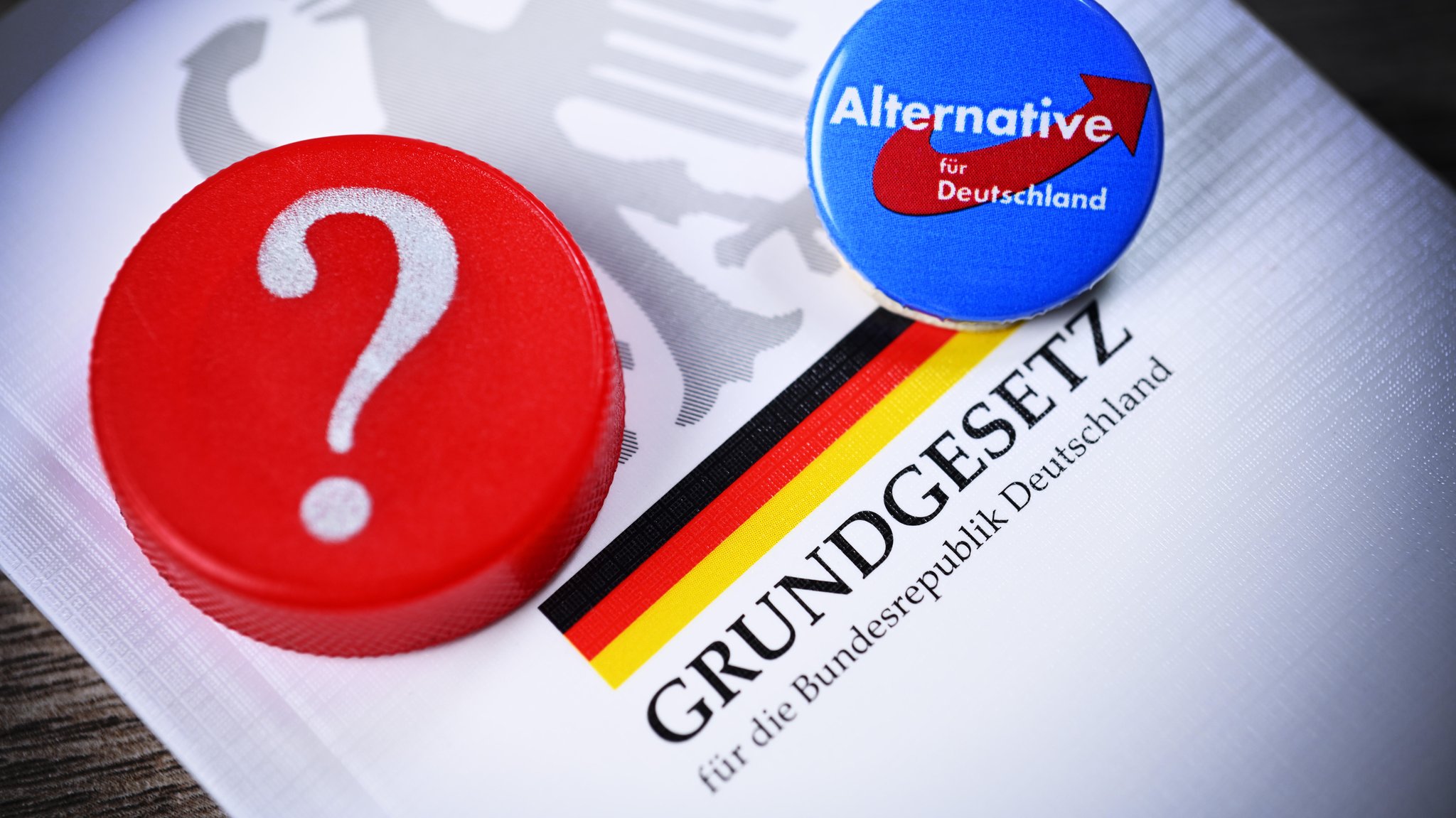 Parteianstecker der AfD und Fragezeichen auf dem deutschen Grundgesetz (Symbolbild)