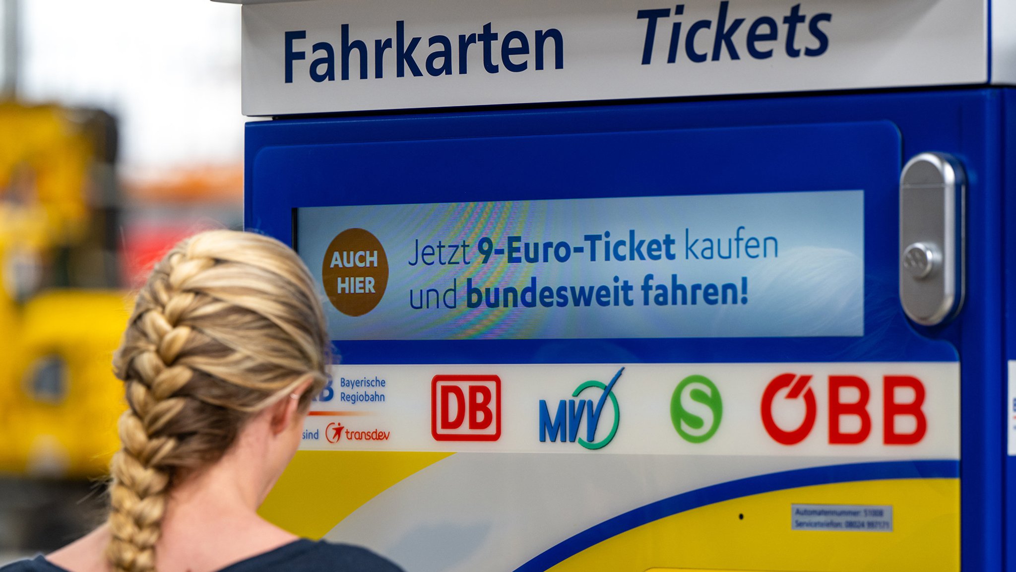 Eine Frau vor einem Ticket-Verkaufsautomaten.