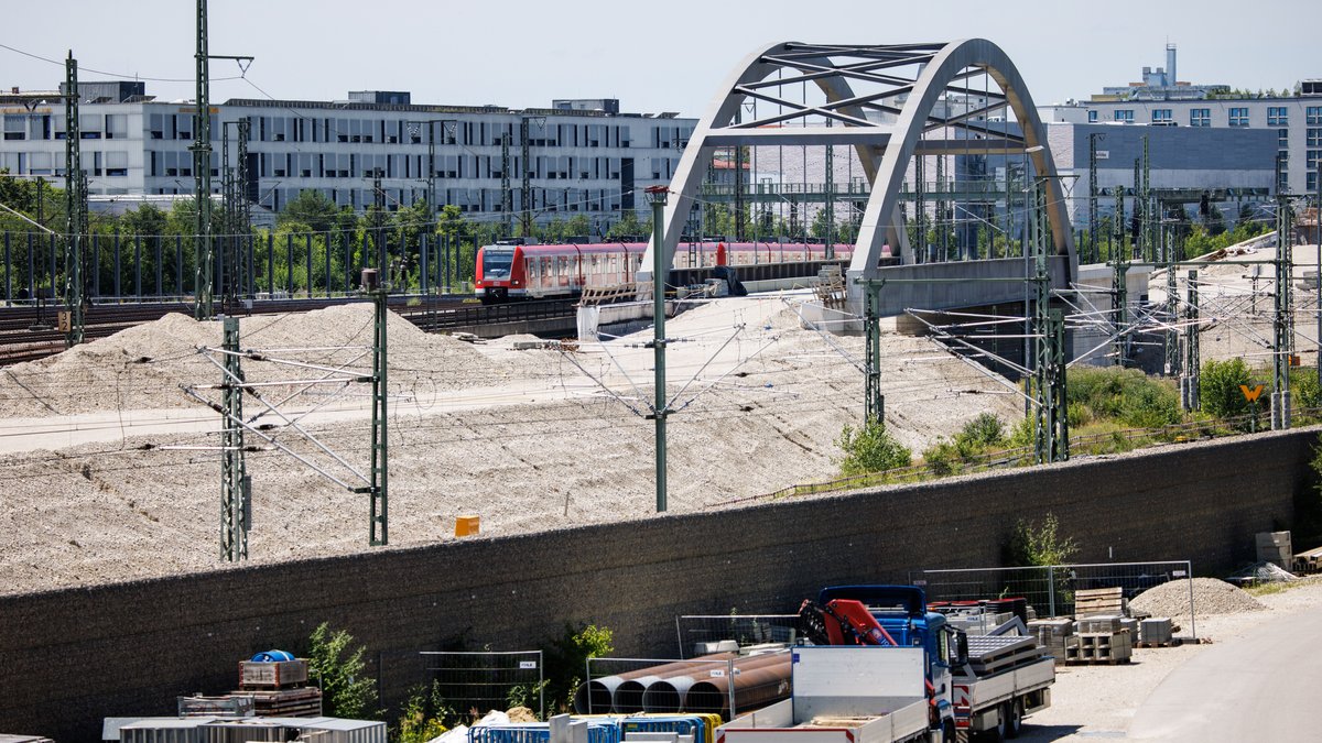 Ein Zug der S-Bahn München fährt an der Baustelle der zweiten S-Bahn-Stammstrecke durch die Münchner Innenstadt vorüber.  im Vordergrund viele Baufahrzeuge. 