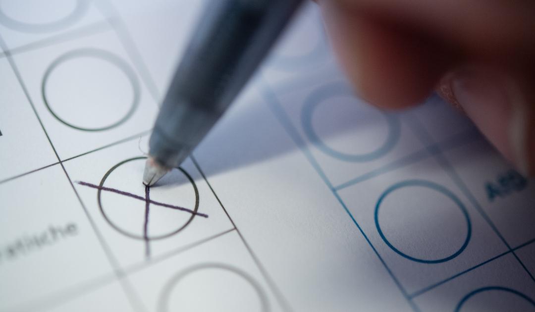 Eine Frau macht ein Kreuz auf einem Wahlzettel.