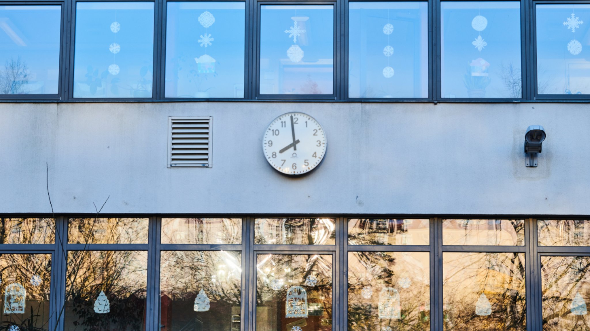 Die Schuluhr an der Fassade einer Grundschule zeigt kurz vor 8 Uhr am Morgen (Symbolbild)