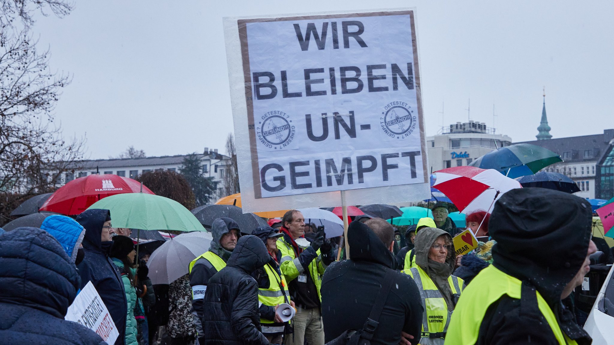 Auf einer Querdenker-Demonstration hät ein Mann ein Schild mit der Aufrschift "Wir bleiben ungeimpft".