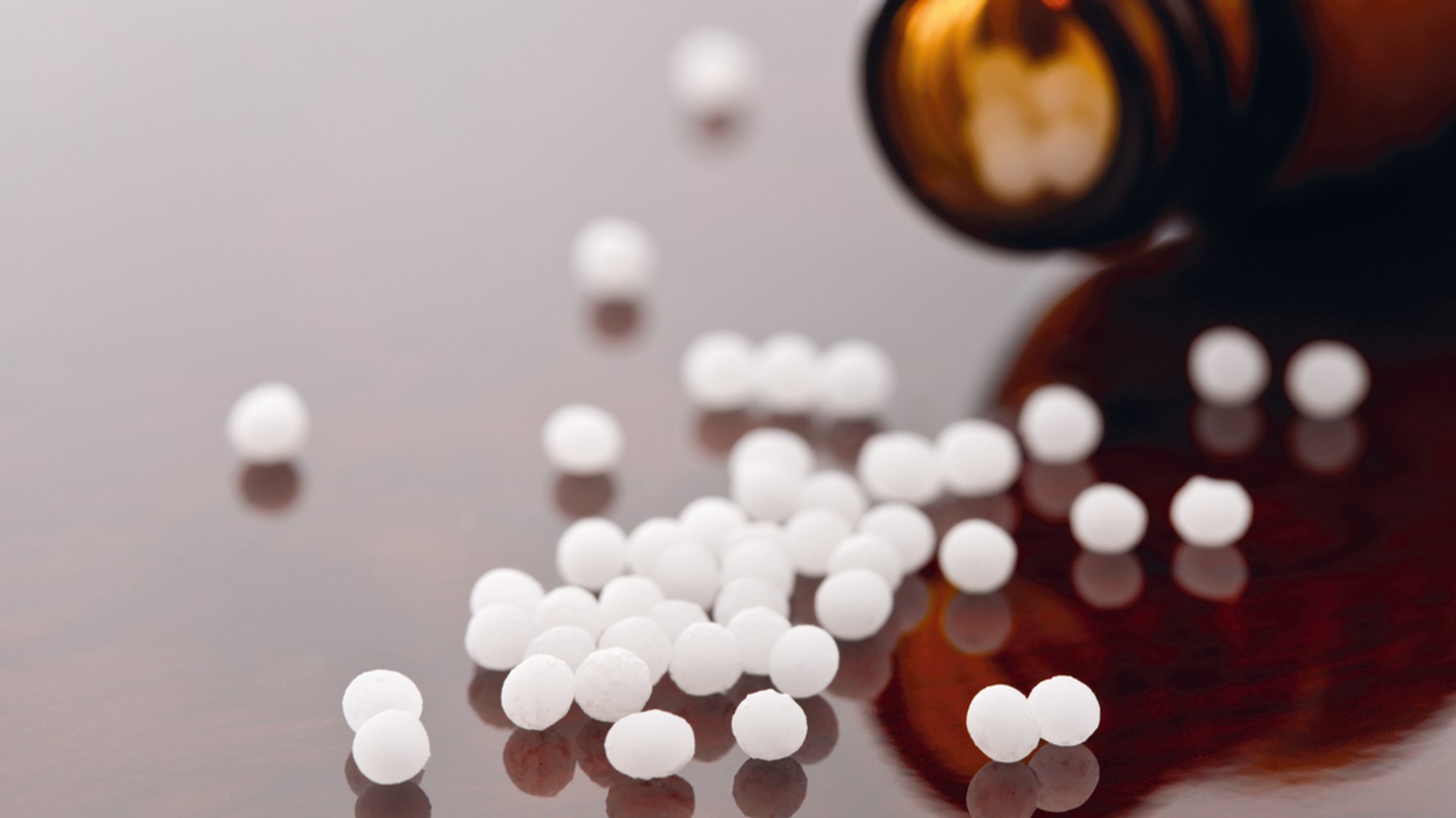 Homöopathische Globuli vor einer Arzneiflasche