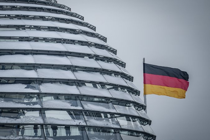 05.12.2023, Berlin: Die Deutschlandfahne weht neben der schneebedeckten Reichstagskuppel im Wind. Am Vormittag findet eine öffentliche Anhörung des Haushaltsausschusses zum Nachtragshaushalt 2023 und zur Aussetzung der Schuldenbremse als digitale Konferenz statt. Foto: Kay Nietfeld/dpa +++ dpa-Bildfunk +++