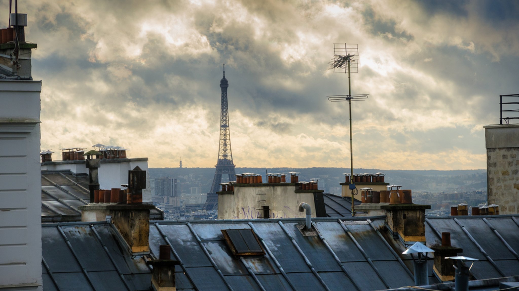 Blick über Häuserdächer hinweg auf den Eiffelturm in Paris