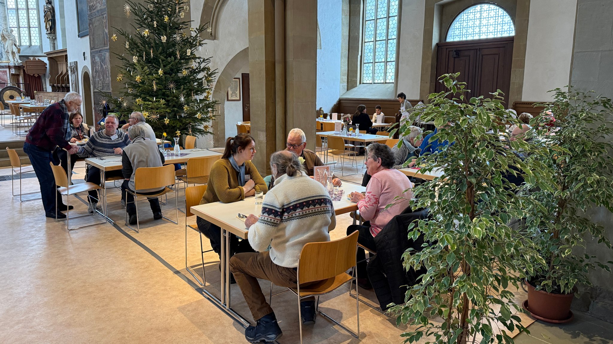 Vesperkirche Schweinfurt: Menschen sitzen an Tischen in einer Kirche und essen.