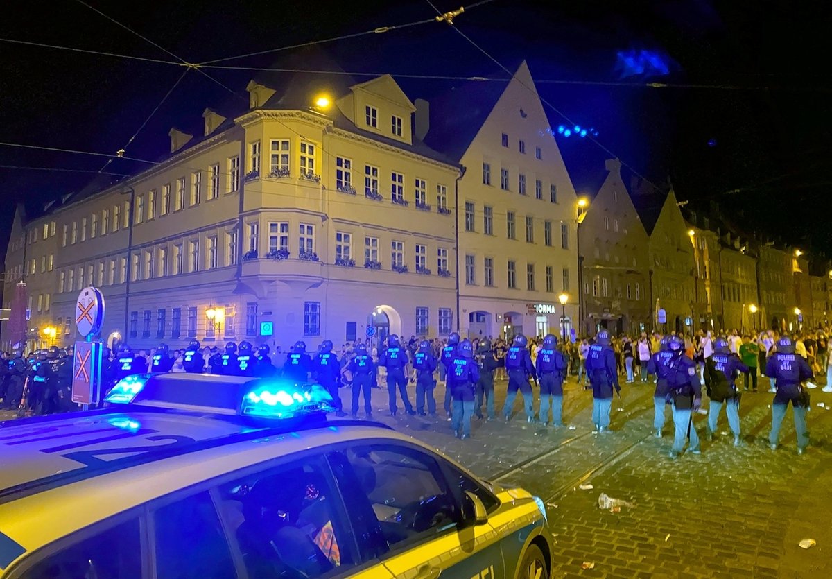 19.06.2020, Bayern, Augsburg: Polizisten stehen an einem Platz in der Innenstadt, wo sich Menschen zum Feiern versammelt haben. Die Polizei hat in der Nacht zu Sonntag eine Ansammlung von hunderten Feiernden aufgelöst. Bei dem Einsatz seien zahlreiche Beamte verletzt worden, sagte ein Polizeisprecher. Auch auf der Seite der Feiernden habe es Verletzte bei dem Einsatz gegeben. (zu dpa: «Wieder Outdoor-Partys und Krawall in Bayern») Foto: Andreas Herz/dpa +++ dpa-Bildfunk +++