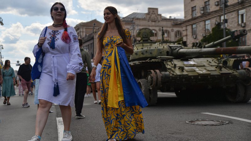 Zwei junge Frauen feiern den ukrainischen Unabhängigkeitstag in Kiew - im HIntergrund steht ein Panzer