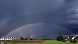 Ein doppelter Regenbogen spannt sich über Wohnhäuser und Ackerflächen. | Bild:picture alliance/dpa | Karl-Josef Hildenbrand