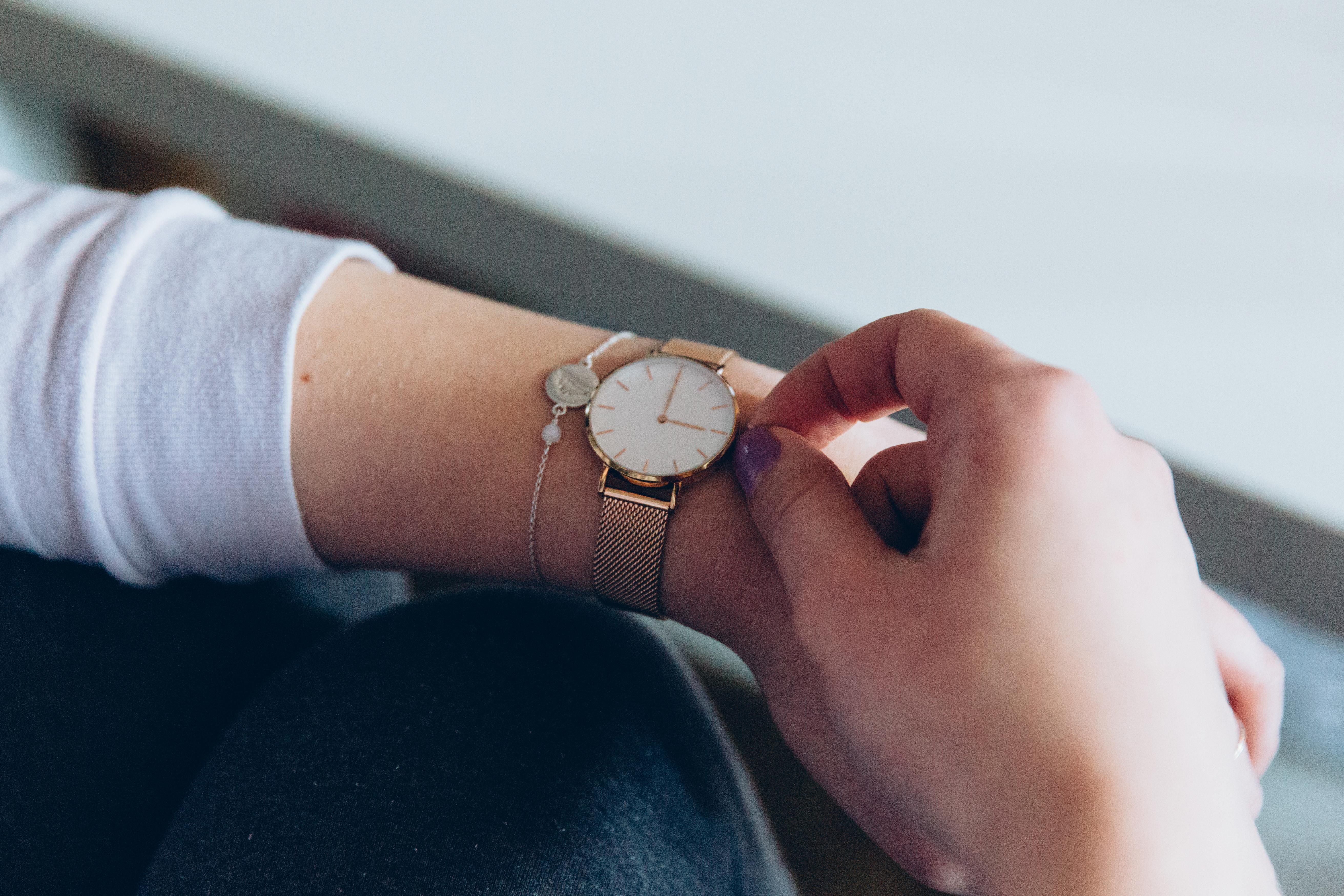Eine Frau stellt die Uhr an ihrem Handgelenk auf die Winterzeit zurück.
