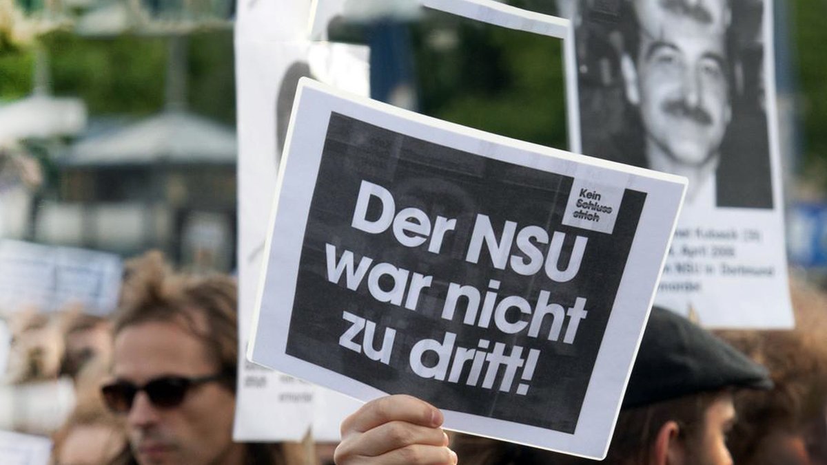 Ein Demonstrant hält ein Schild mit der Aufschrift "Der NSU war nicht zu dritt" in die Höhe