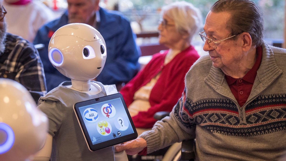 Symbolbild: Humanoider Roboter mit Bewohner eines Alten- und Pflegeheims