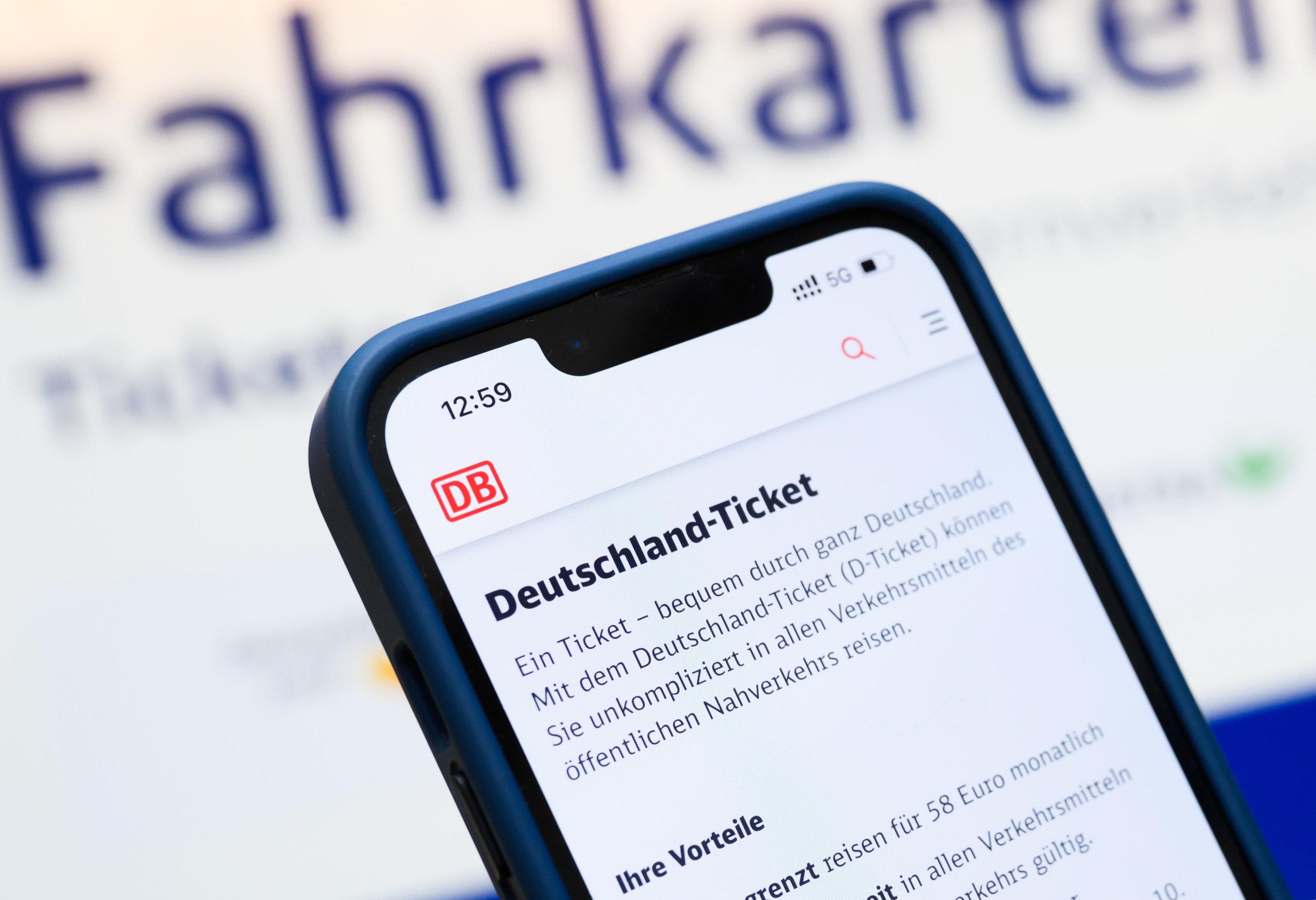 Eine Person hält am Hauptbahnhof ein Smartphone in der Hand, auf dessen Display eine Information zum Kauf des Deutschlandtickets zu sehen ist.