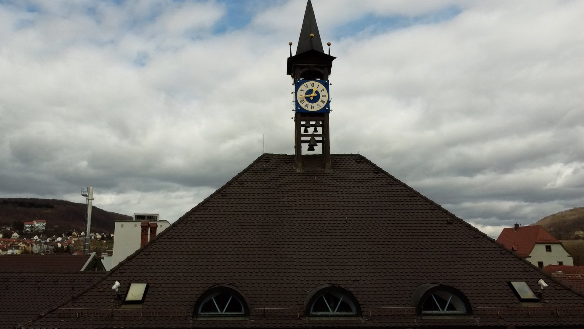 Das Rathausdach in Treuchtlingen mit einer Uhr und Glocken.