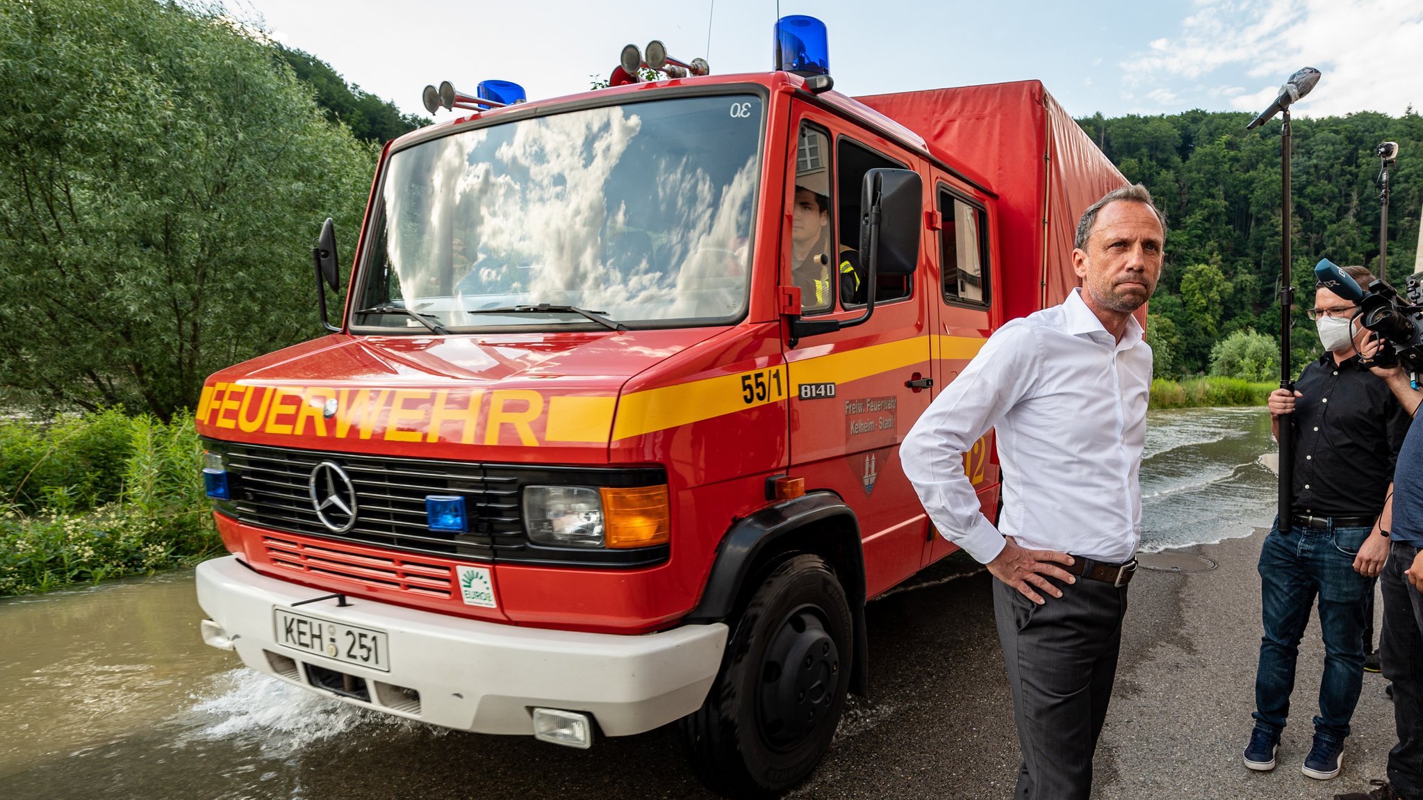 Bayerns Umweltminister Glauber vor einem Feuerwehrauto an der Hochwasser führenden Donau vor dem Kloster Weltenburg.