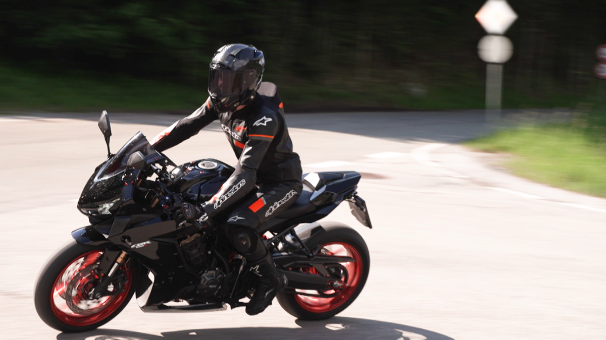 Fahrender Motorradfahrer in schwarzer Ledermontur mit Helm