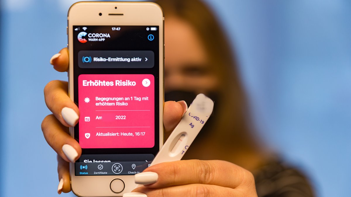 Frau hält Smartphone mit geöffneter Corona-Warn-App in der Hand