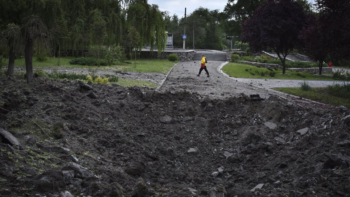 Saporischschja: Eine Frau geht vor einem Krater, der durch einen russischen Raketenangriff verursacht wurde.