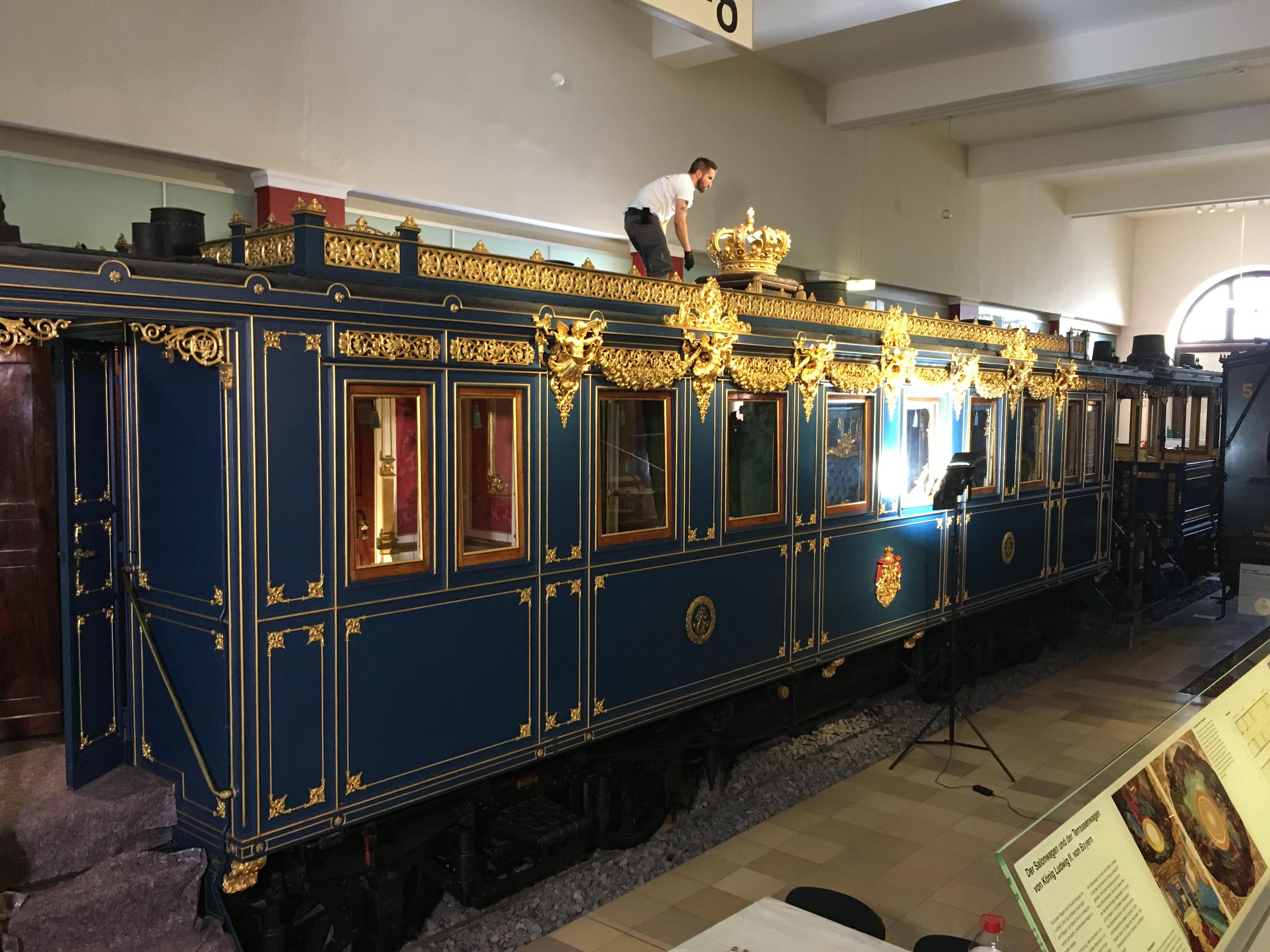 Ein Mann steht auf einem vergoldeten Luxus-Waggon von König Ludwig II.