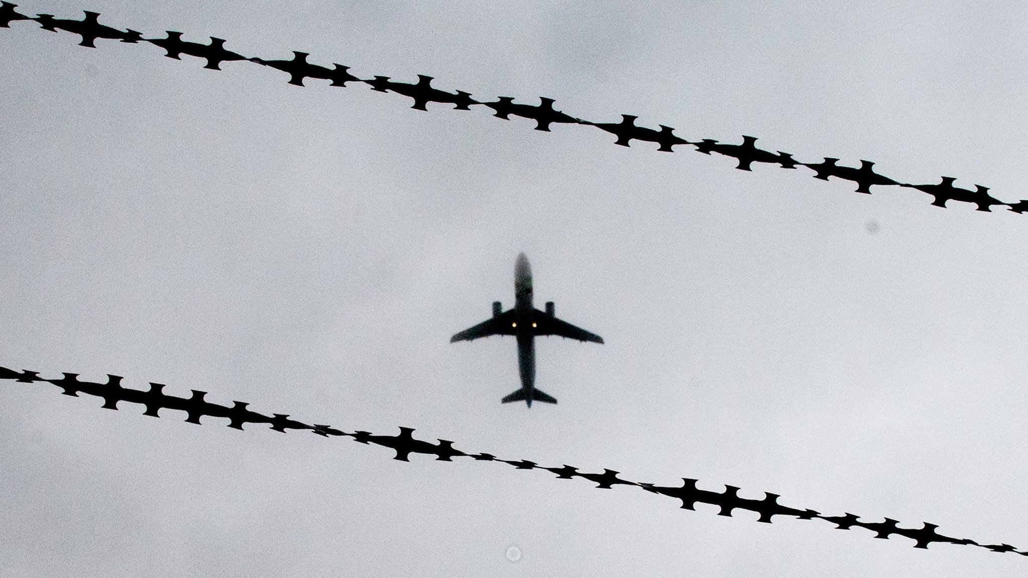 Flugzeug in der Luft zwischen Stacheldraht.