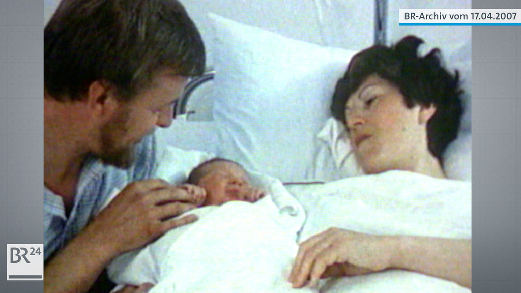 Vater links am Bett, Retortenbaby kurz nach der Geburt, Mutter im Kindbett rechts