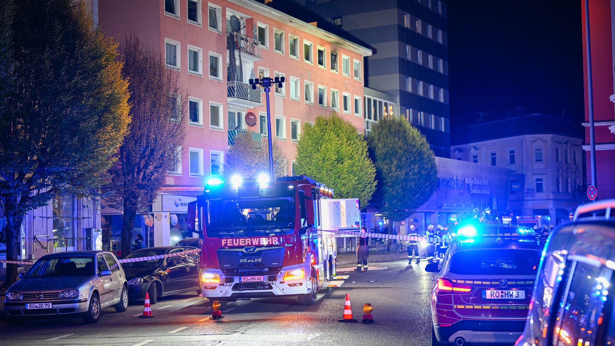 Feuerwehr- und Polizeifahrzeuge vor dem Mehrfamilienhaus, in dem das Feuer ausgebrochen war. 