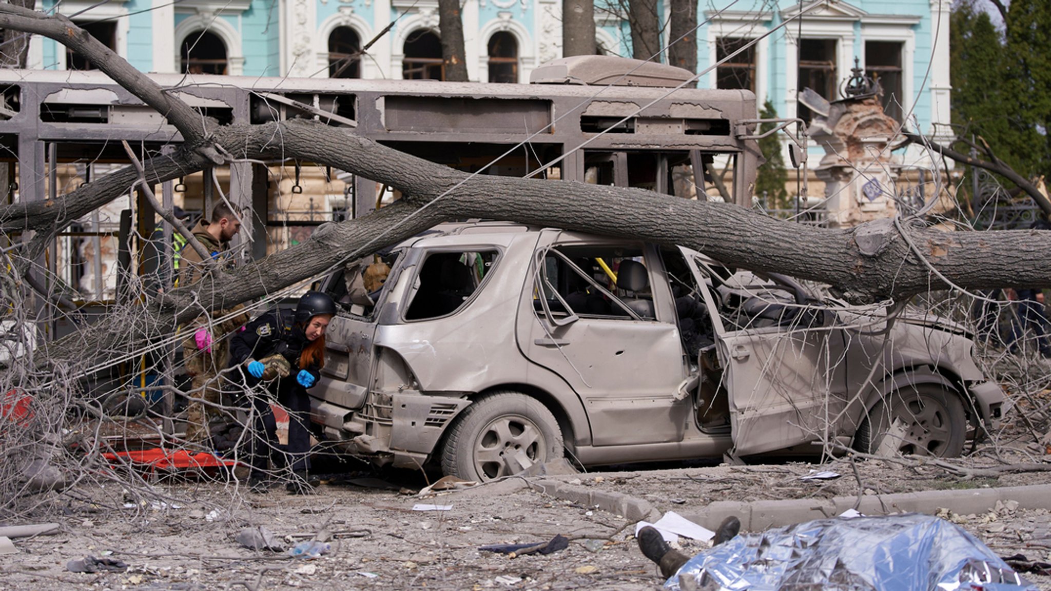 13.04.2025, Ukraine, Sumy: Eine abgedeckte Leiche und zerstörte Autos sind nach einem schweren russischen Raketenschlag zu sehen.