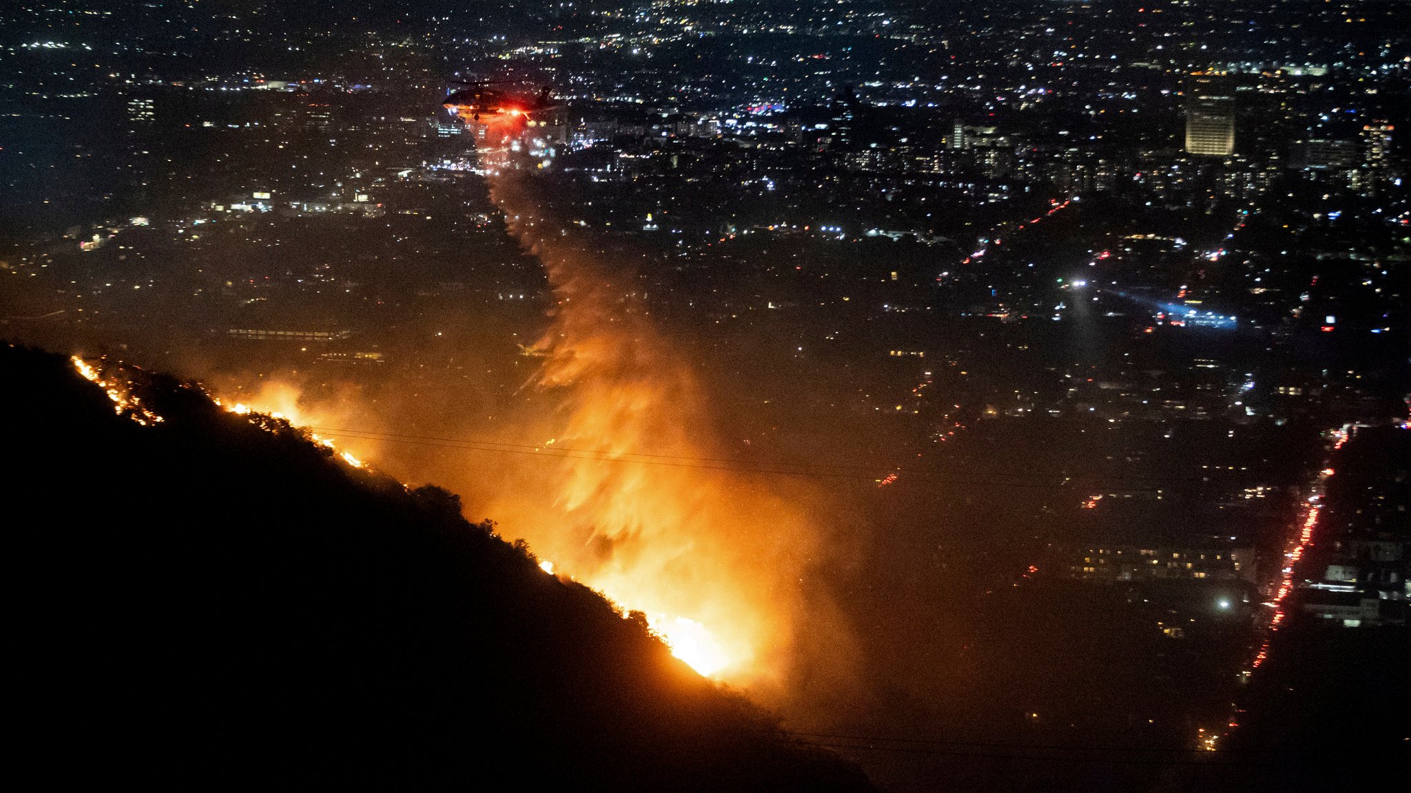 Ein Hubschrauber wirft Wasser auf das brennende "Sunset Fire" in den Hollywood Hills.