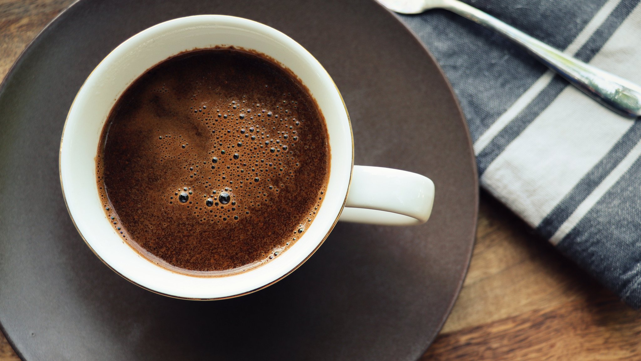 Eine heiße Tasse Kaffee steht auf einem Holzrisch