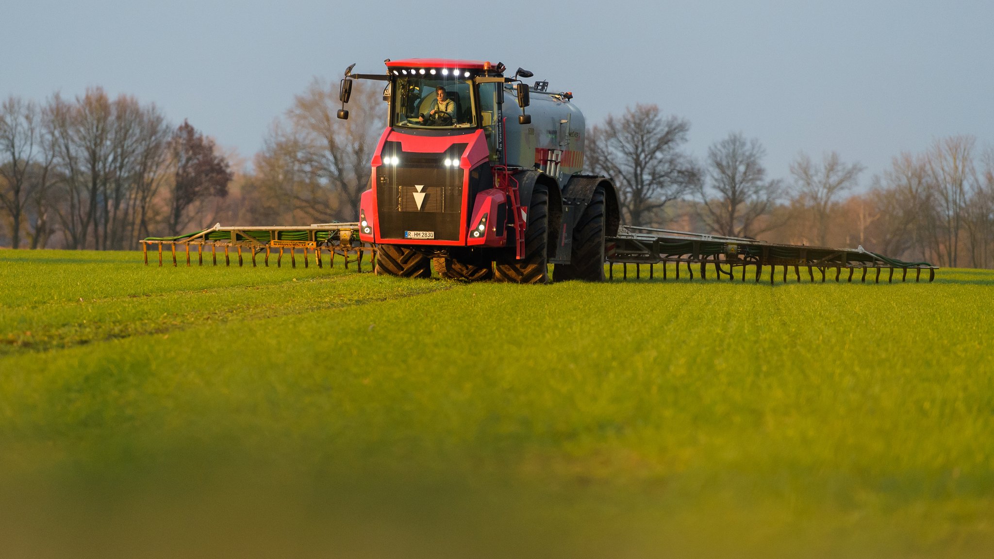 Ein Landwirt bringt mit seinem Gespann Gülle im sogenannten Schleppschuh-Verfahren auf einem Feld aus. (z